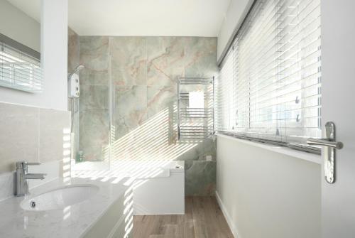 a white bathroom with a sink and a window at Sunset Apartment - 7th Floor Double Tree in Brighton & Hove