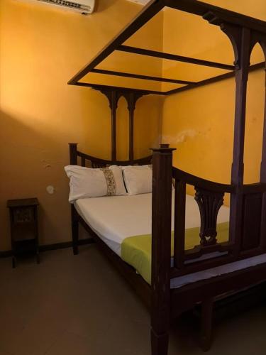 a bedroom with a wooden canopy bed with white pillows at Arizona apartment in Zanzibar City