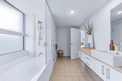a white bathroom with two sinks and a shower at Salt & Sea in Airlie Beach