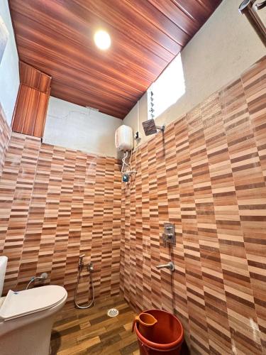 a bathroom with a toilet and a wooden wall at Hotel Jatra in Sillod