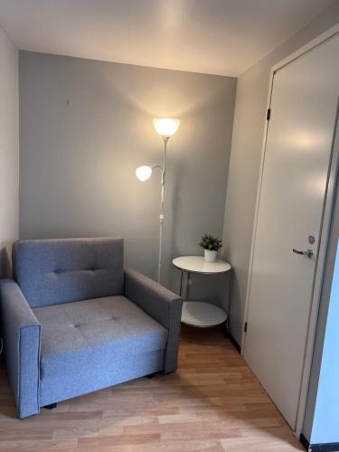 a living room with a blue chair and a lamp at Hostelli Palonkortteeri in Ilmajoki