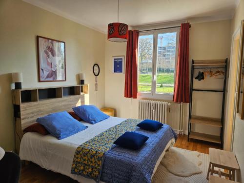a bedroom with a bed with blue pillows on it at La Roseraie in Le Mans