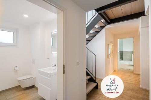 a bathroom with a toilet and a sink and a staircase at Marissa Resort in Lembruch