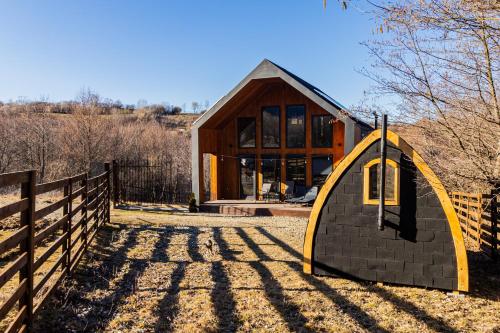 a small house with a yellow structure next to a fence at Cabana Alpinest & Sauna in Bran