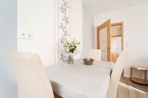 a white dining room table with a vase of flowers on it at Haus Tweeflunken Wohnung 1 in Kellenhusen