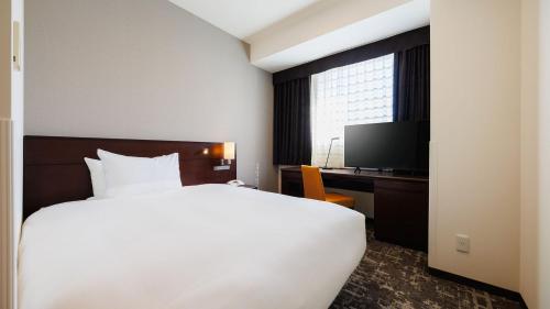 a bedroom with a bed and a desk and a television at JR-East Hotel Mets Yokohama Tsurumi in Yokohama