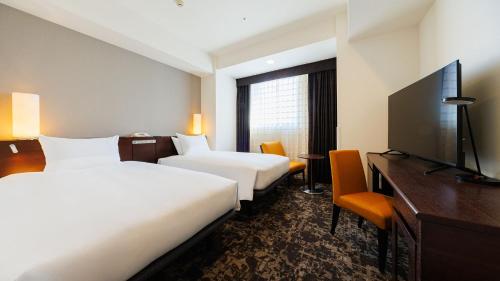 a hotel room with two beds and a flat screen tv at JR-East Hotel Mets Yokohama Tsurumi in Yokohama