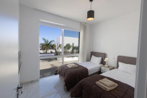 a bedroom with two beds and a large window at Vie Bleu Villas in Protaras