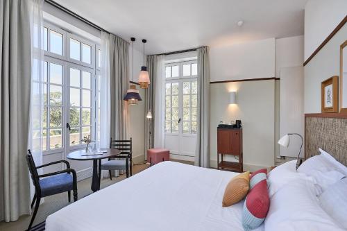 a bedroom with a large bed and a table and chairs at Villa Arthus-Bertrand in Noirmoutier-en-l'lle