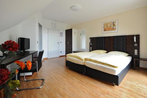 a large bedroom with a large bed and a desk at Hotel und Kongresszentrum Wanderath in Baar