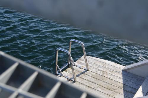a wooden dock with a metal hand rail on the water at Salt & Sill in Klädesholmen