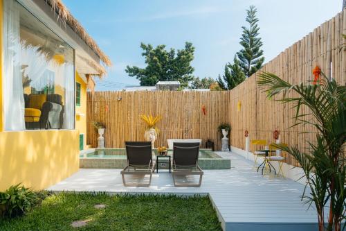 a patio with two chairs and a table next to a fence at Lime Splash Private pool in Choeng Mon Beach