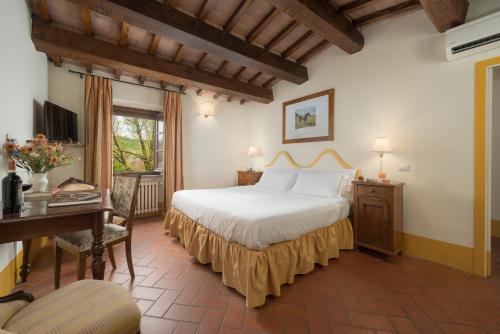a hotel room with a bed and a desk and a desk at Relais Poggio Borgoni in San Casciano in Val di Pesa