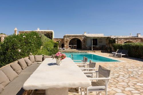 a table with chairs next to a swimming pool at Villa Iliablue in Vrachonisída Petrokáravo
