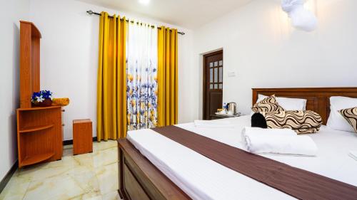a bedroom with a large bed and yellow curtains at Villa Swallow Nest in Sigiriya