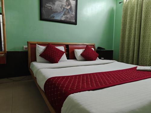a bedroom with a bed with red and white pillows at Oasis Hotel and Restaurant in Siliguri