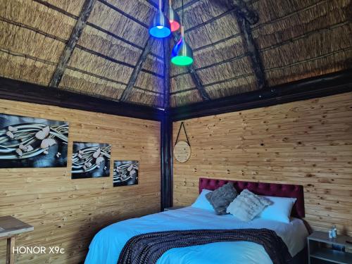 a bedroom with a bed and a thatched roof at Oluhle Resort in Hammanskraal