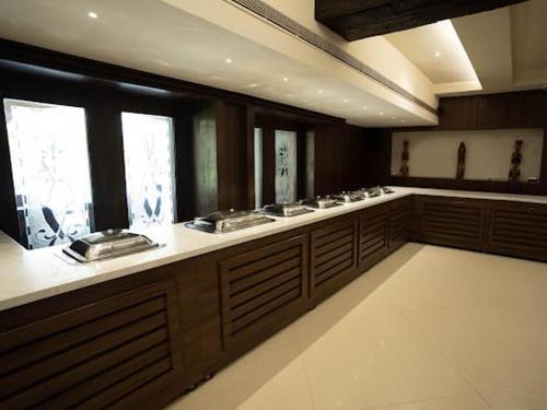 a large kitchen with wooden cabinets and sinks and windows at Grand Heritage Narmada Jacksons in Jabalpur