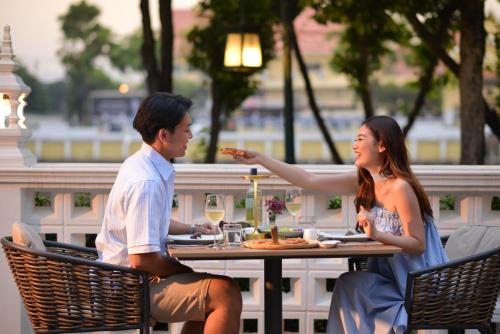 a man and woman sitting at a table eating food at March Hotel & Suite Riverside in Chiang Mai