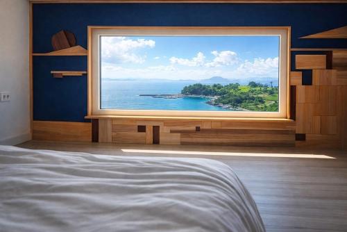a bedroom with a large window with a view of the ocean at Orchard 123 Private Pension in Yeosu