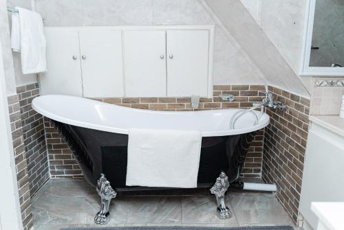 a bath tub in a bathroom with a brick wall at Hoyozela in Hartbeespoort