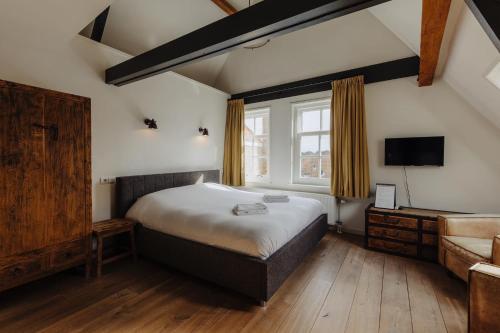 a bedroom with a bed and a tv and a couch at Hotel De Heeren in Veere