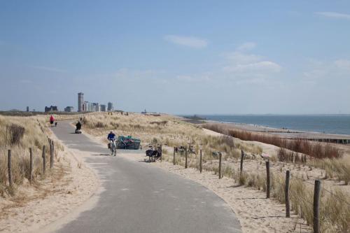 a person riding a bike down a road next to the beach at Welcome in - Appartement dichtbij het strand met balkon I Burg van Woelderenlaan 100-23 Vlissingen in Vlissingen