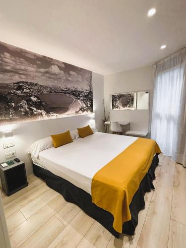 a bedroom with a large bed with a yellow blanket at Pension y Apartamentos Txingurri Experience in Astigarraga