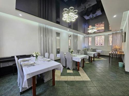 ein Esszimmer mit weißen Tischen und Stühlen und einem Kronleuchter in der Unterkunft Libra in Karolinów