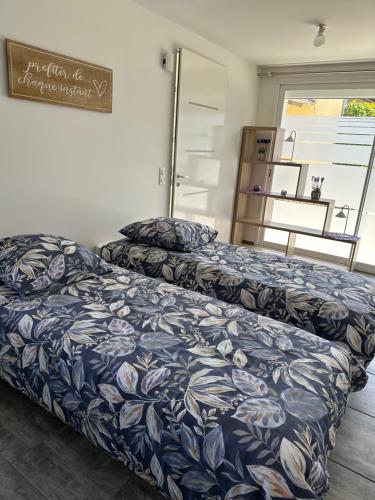 a bedroom with two beds with a blue and white comforter at LAVANDE studio 4 personnes in Château-Arnoux-Saint-Auban