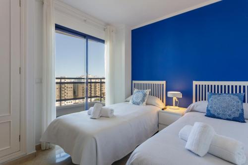 two beds in a room with a blue wall at Ag Eden Resort in Gandía