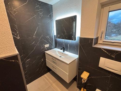 a bathroom with a white sink and a black wall at Ferienwohnung Grünblick am Katschbach in Teufenbach