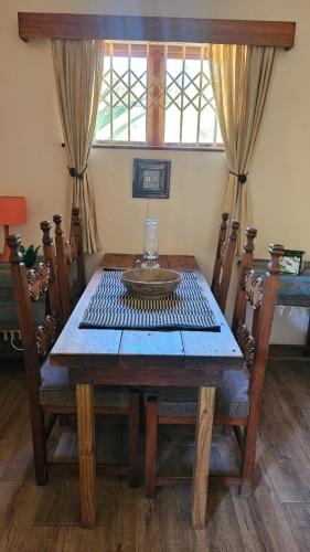 a wooden table with chairs and a glass bowl on it at Alpaca Self Catering Cottage Kleinmond in Kleinmond