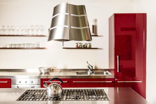 uma cozinha vermelha com um lavatório e uma panela no fogão em Villa Uliveto em Staffolo