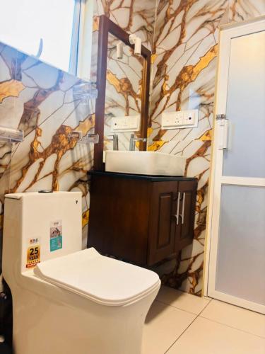 a bathroom with a toilet and a wall with a mural at Hill Cool Hotel & Restaurant in Hatton