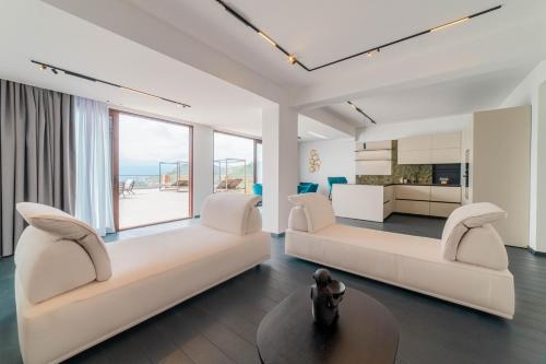 a living room with two white couches and a kitchen at Dimora Eledia in Taormina