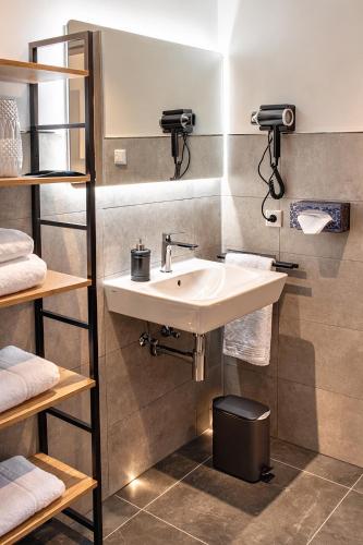 a bathroom with a white sink and shelves at Luxuriöse, 1-2-Zimmer-Apartments 30-55 qm in Fürstenau