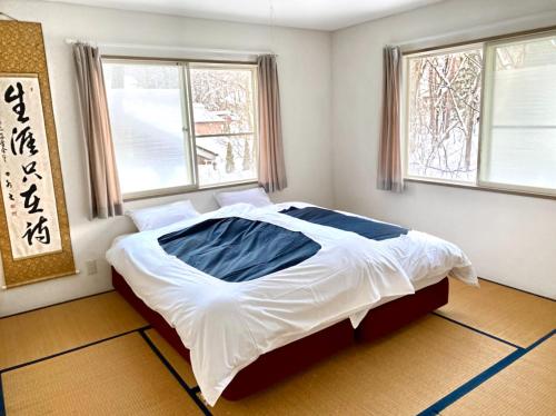 a bedroom with a large bed in a room with windows at Hakuba Haven Lodge in Hakuba