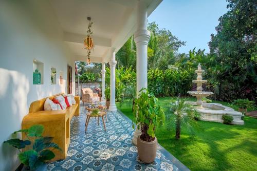 a living room with a couch and a fountain at SaffronStays Sweet Mango - 4BR Goan Villa w Private Pool, Mango Garden, Bar Gazebo & Vibrant Interiors Near Beaches in Parra