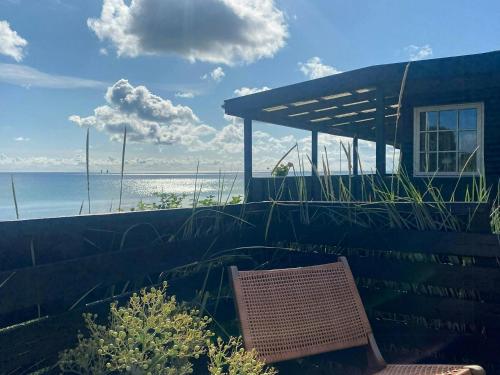 a chair sitting in front of a building with the ocean at Breathtaking Sea View At Dinestrup Beach in Ullerslev