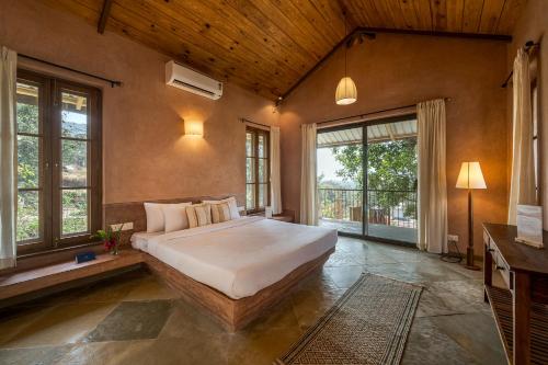 a bedroom with a large bed in a room with windows at SaffronStays Rustic Trails in Mulshi
