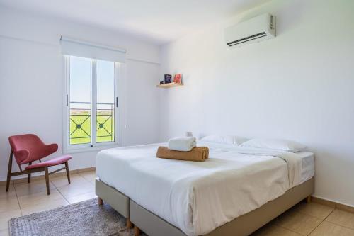 a white bedroom with a bed and a red chair at 2BR Apartment with Amazing View and Pool in Kiti in Kiti