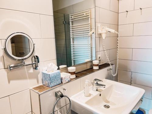 a white bathroom with a sink and a mirror at Feriendorf Marienhof C2 Marieke in Borkum
