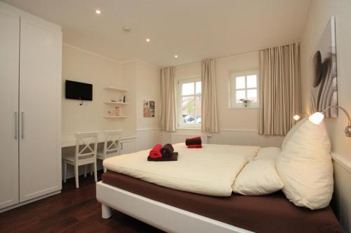 a bedroom with a large white bed and a desk at Feriendorf Marienhof C2 Marieke in Borkum