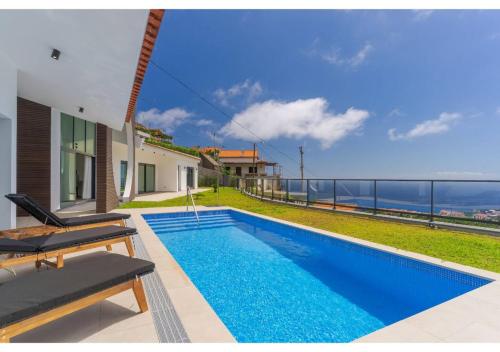 a swimming pool with a view of the ocean from a house at The pool house in Ponta de Sol in Funchal
