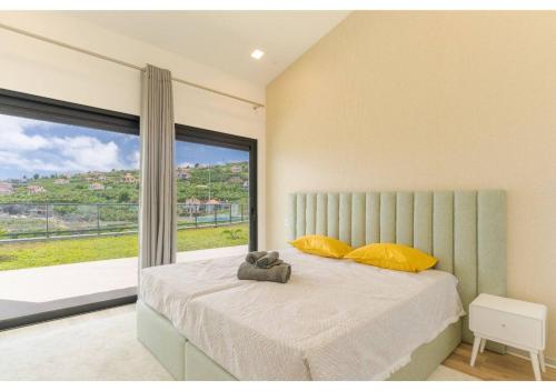 a bedroom with a bed with yellow pillows and a window at The pool house in Ponta de Sol in Funchal