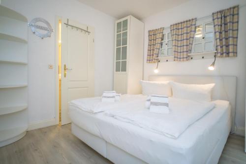 a white bedroom with a large white bed with two towels at Am Austernstrand in List