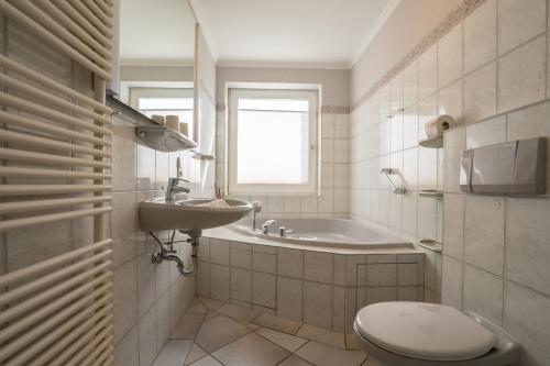 a bathroom with a sink and a toilet and a tub at Lister Reede Garten in List