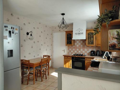 a kitchen with a table and a white refrigerator at Spacieuse maison "Des 3 filles" pour 6 personnes in Ally