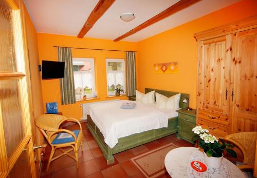 a bedroom with a bed and a tv and a table at Hotel/Pension Bradhering in Ahrenshoop